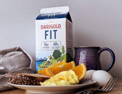 A plate of breakfast food, eggs, a mug and a carton of Darigold FIT milk
