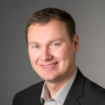 Head shot of smiling man with a solid grey background