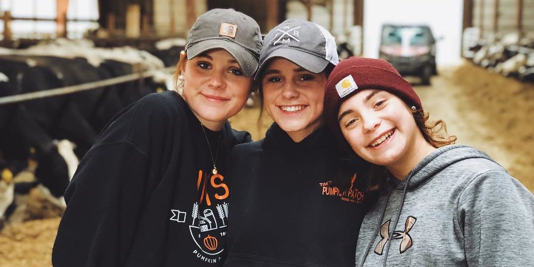 Three girls pose in a barn