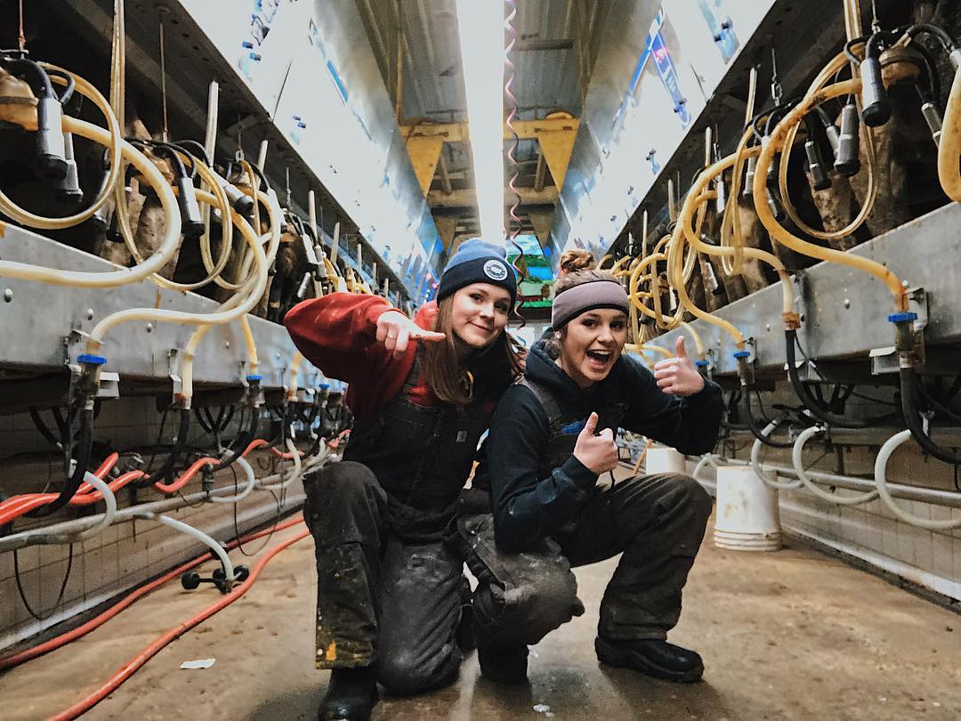 Two girls pose in a milking parlor