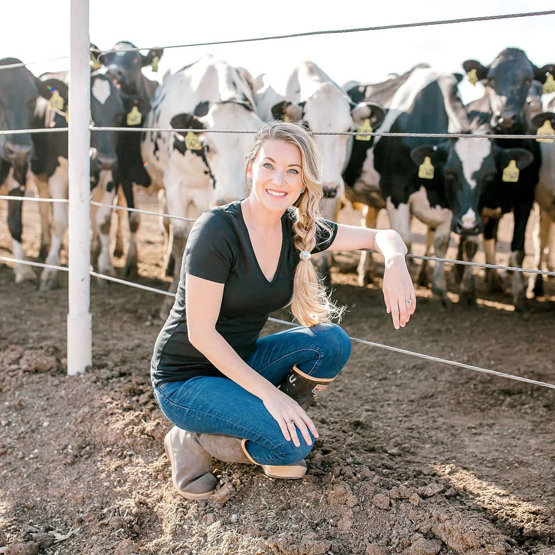 A woman poses in front of a group of cows