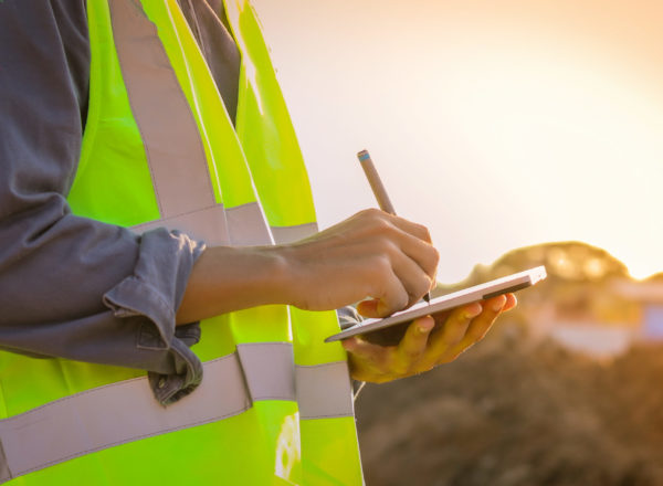 Engineer with a hardhat using a tablet at a construction site