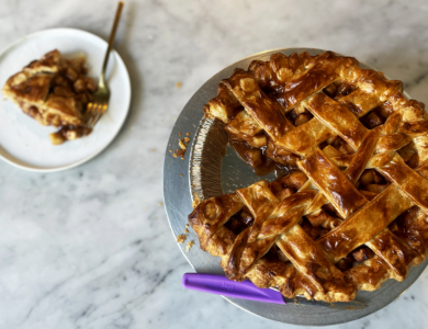 Photo of a apple pie with a slice cut out and placed on a nearby plate