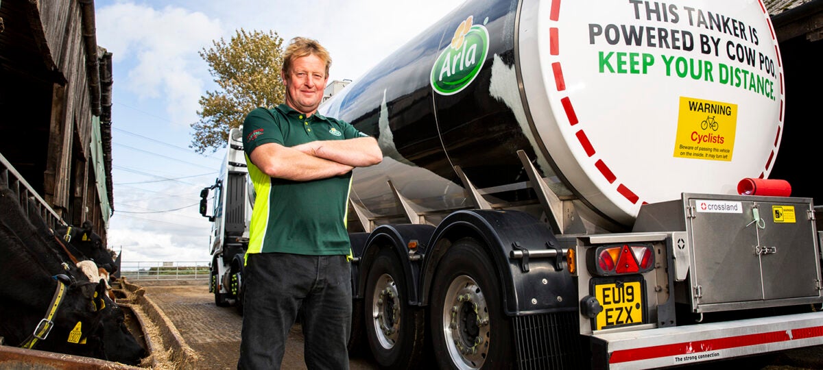 A man standing next to a milk truck poses for the camera