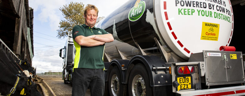 A man standing next to a milk truck poses for the camera