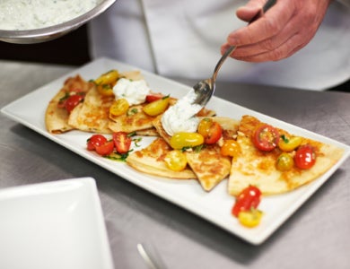 Quesadilla served on a long square plate with cottage cheese and tomatoes
