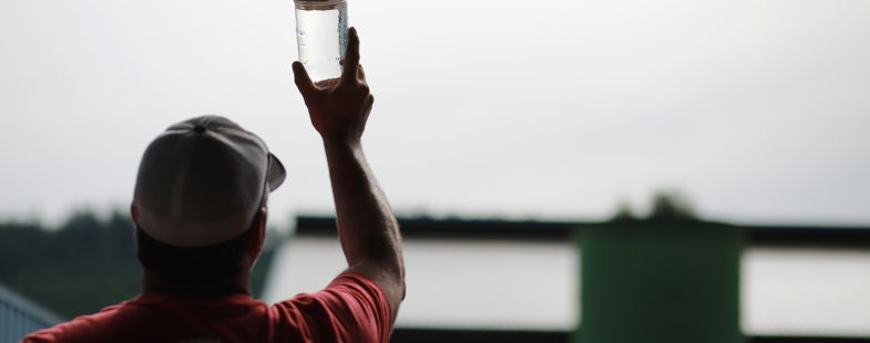 Man holding jar of clean water up to the sky