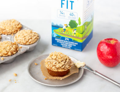 Muffins arranged on a table with an apple and milk carton