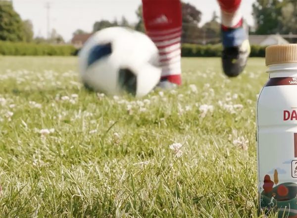 Someone with red soccer socks kicks the ball near a bottle of Darigold FIT