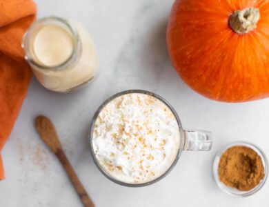 A coffee with creamer, pumpkin and fall-colored styling on marble