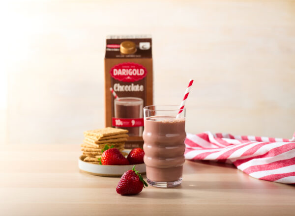 Creative product shot featuring Darigold Chocolate Milk with strawberries and graham crackers