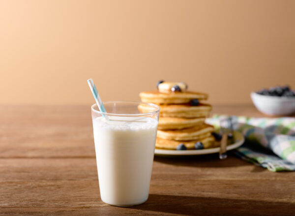 Creative shot of a glass of milk with blueberry pancakes