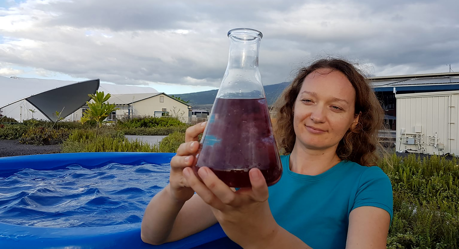 Women holding a giant flask of red macro algae