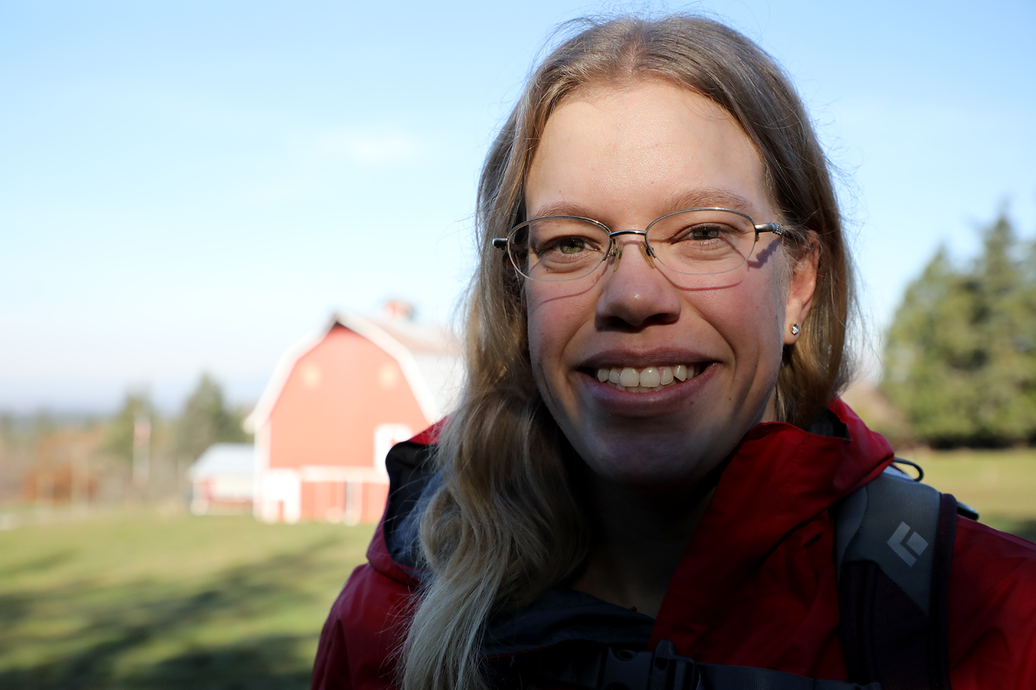 Women wearing glasses poses in front of a red barn