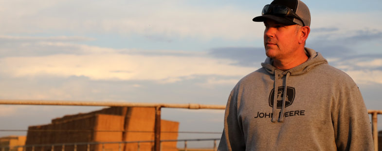 Farmer standing in front of a hay stack