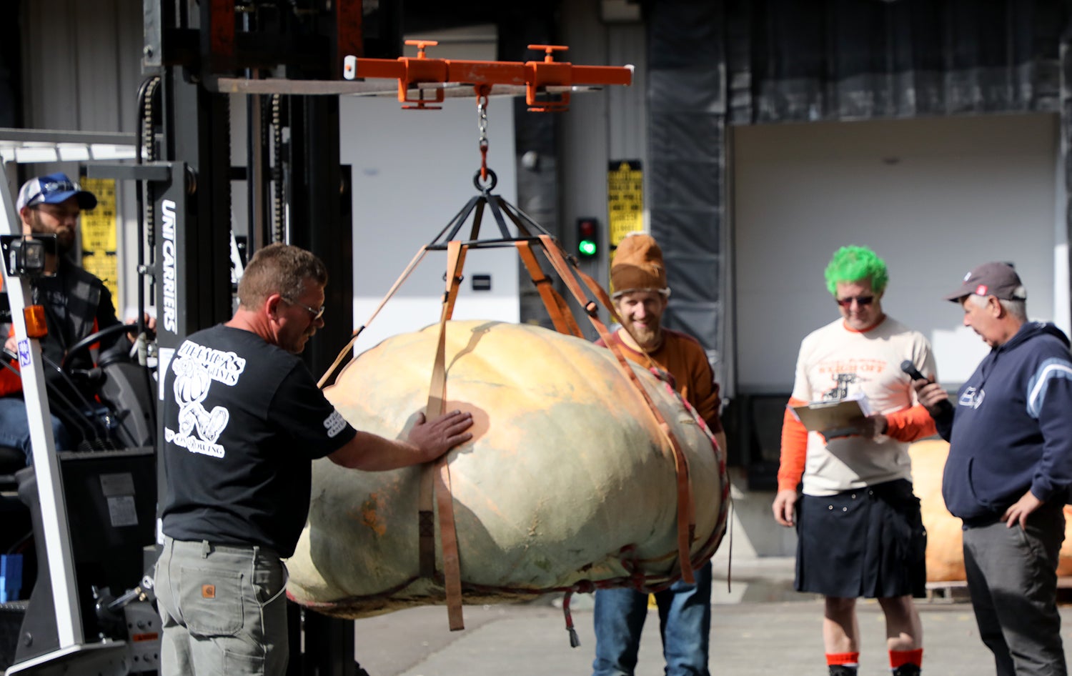 Several men crowding a giant pumpkin