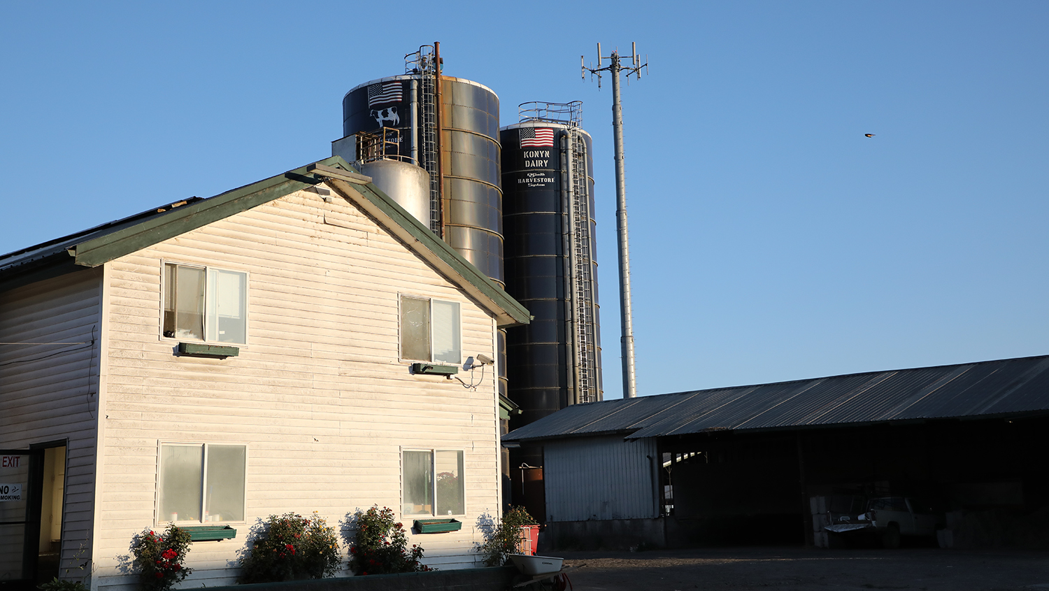 Photo of a farm house and silos at sunrise