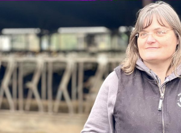 A woman poses in front of dairy cows