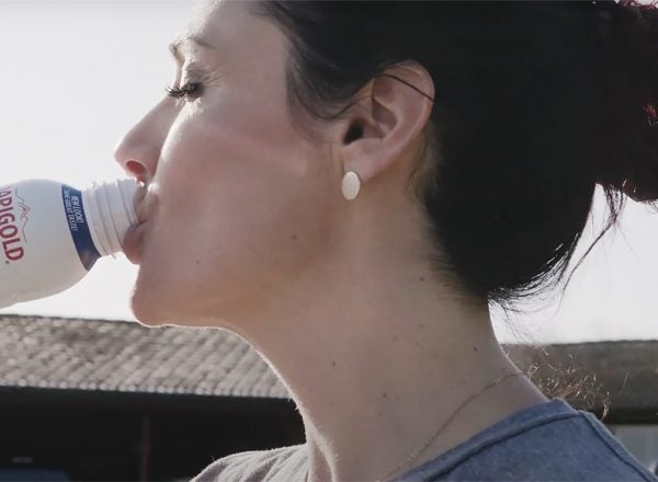A side profile of a woman drinking Darigold FIT milk