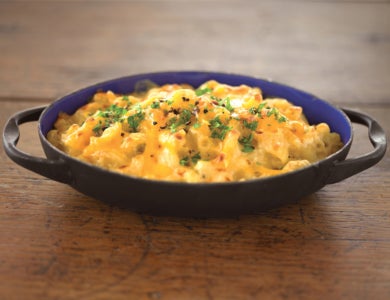 Small cast iron dish with Mac and cheese on a wooden shelf