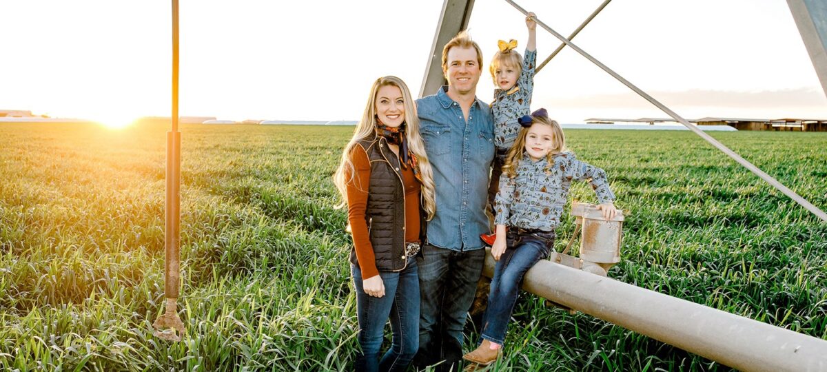 A family poses in a field at sunset