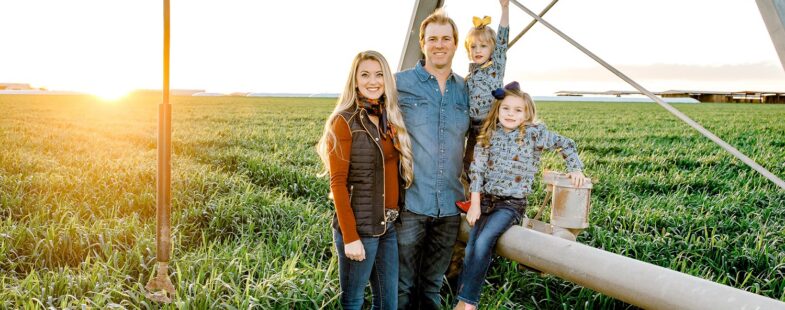 A family poses in a field at sunset