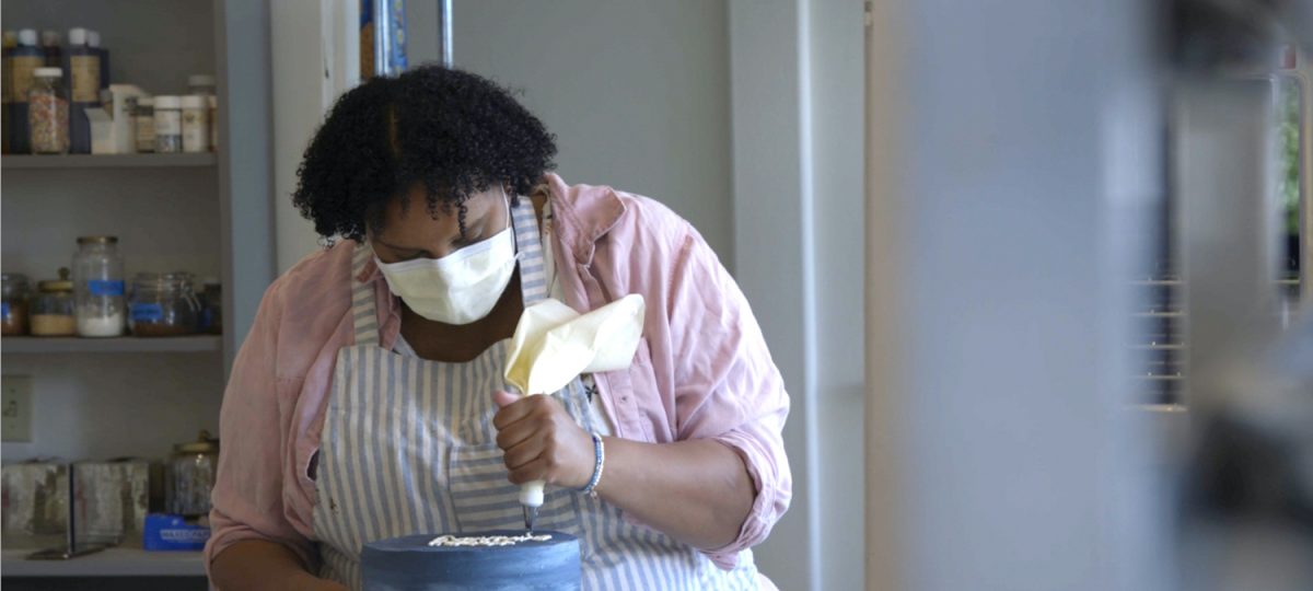 A black woman ices a cake