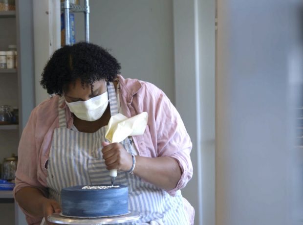 A black woman ices a cake