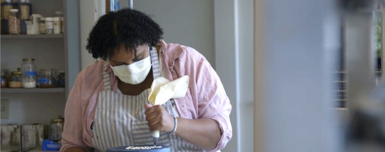 A black woman ices a cake