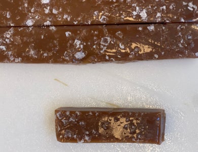 Two long strips and one piece of espresso caramels against a marble table