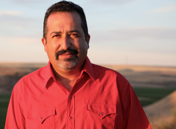 Man in red shirt poses outside for the camera