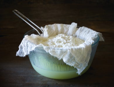 Making ricotta cheese on a dark wooden surface