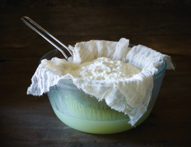 Making ricotta cheese on a dark wooden surface