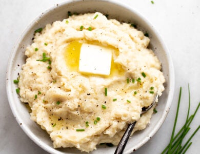 A bowl of mashed potatoes and cauliflower with butter and chives