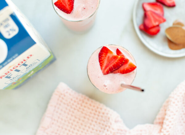 Two strawberry banana smoothies with a bottle of Darigold FIT milk