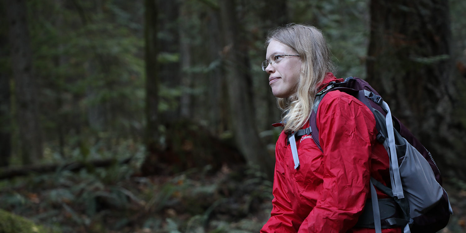 Woman in red jacket sits in a forest