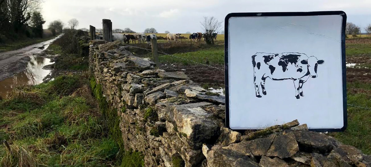 A painted Holstein cow on a sign in the English countryside