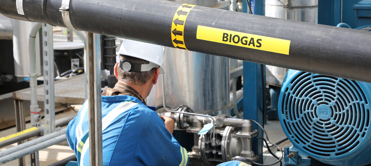 Man wearing blue uniform working on biogas equipment