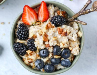 A bowl of oatmeal with blueberries, blackberries, strawberries and nuts