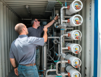 Two men in a small trailer full of equipment