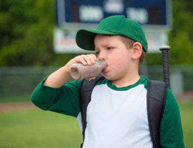 A child drinks chocolate milk after a baseball game