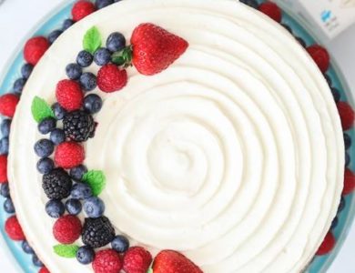 A cake topped with fruit and flanked by a half pint of Darigold cream