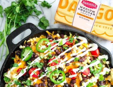 A cast iron pan filled with nachos and other colorful ingredients