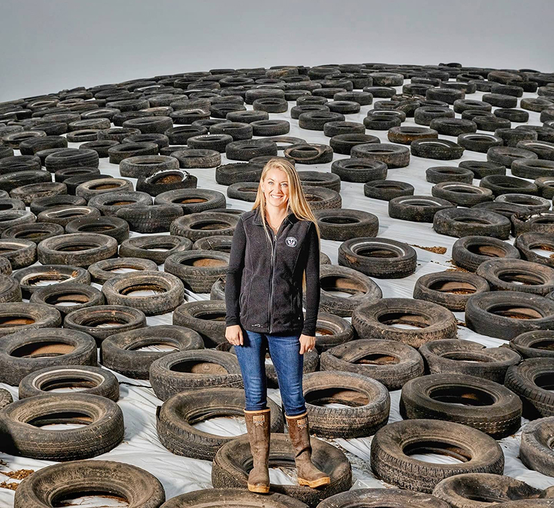 A woman stands on a mountain of recycled tires