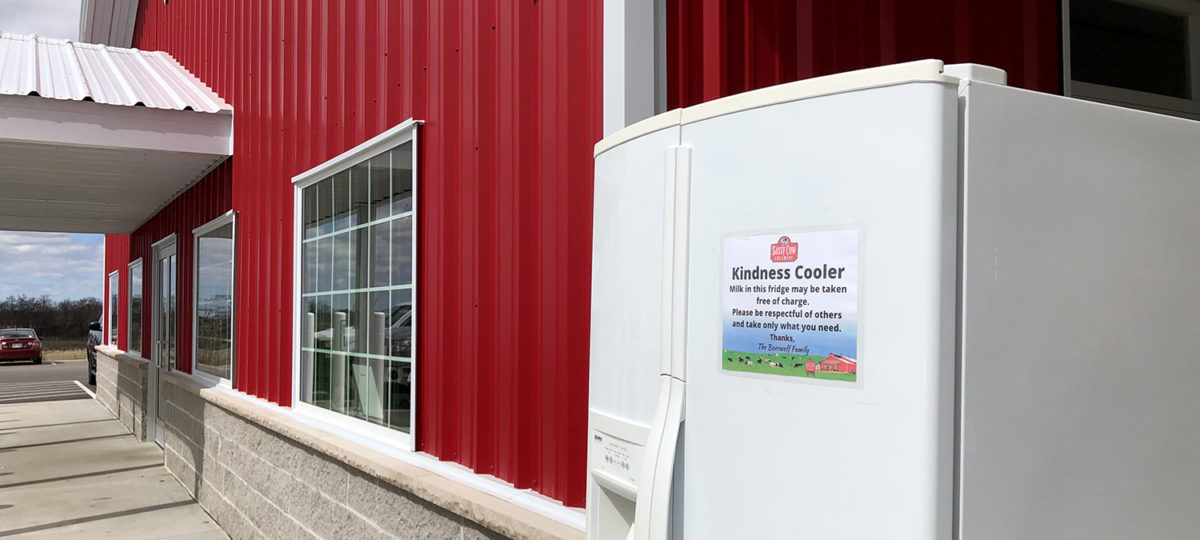 A fridge stands outside a cherry-red building