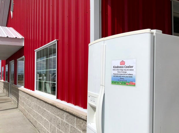 A fridge stands outside a cherry-red building