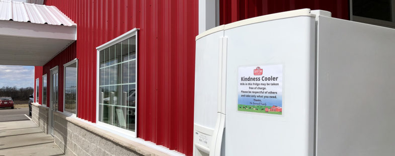 A fridge stands outside a cherry-red building